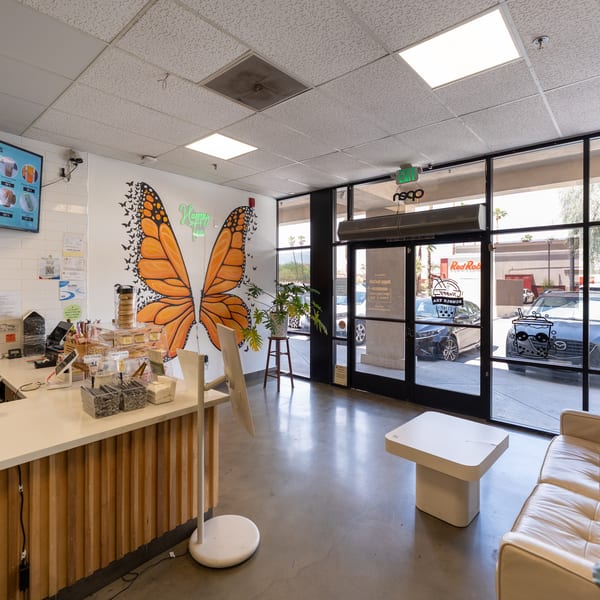 The interior of Happy Tea Cafe features a counter, a large butterfly mural, and a seating area.