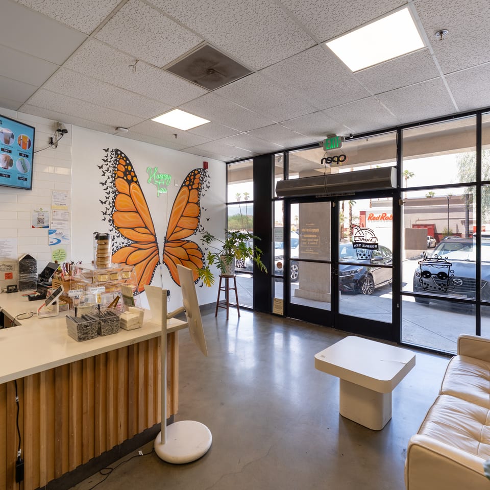 The interior of Happy Tea Cafe features a counter, a large butterfly mural, and a seating area.