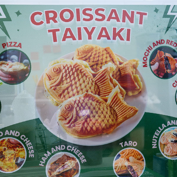 A menu board displays various croissant taiyaki flavors, including pizza, custard, and Nutella banana.