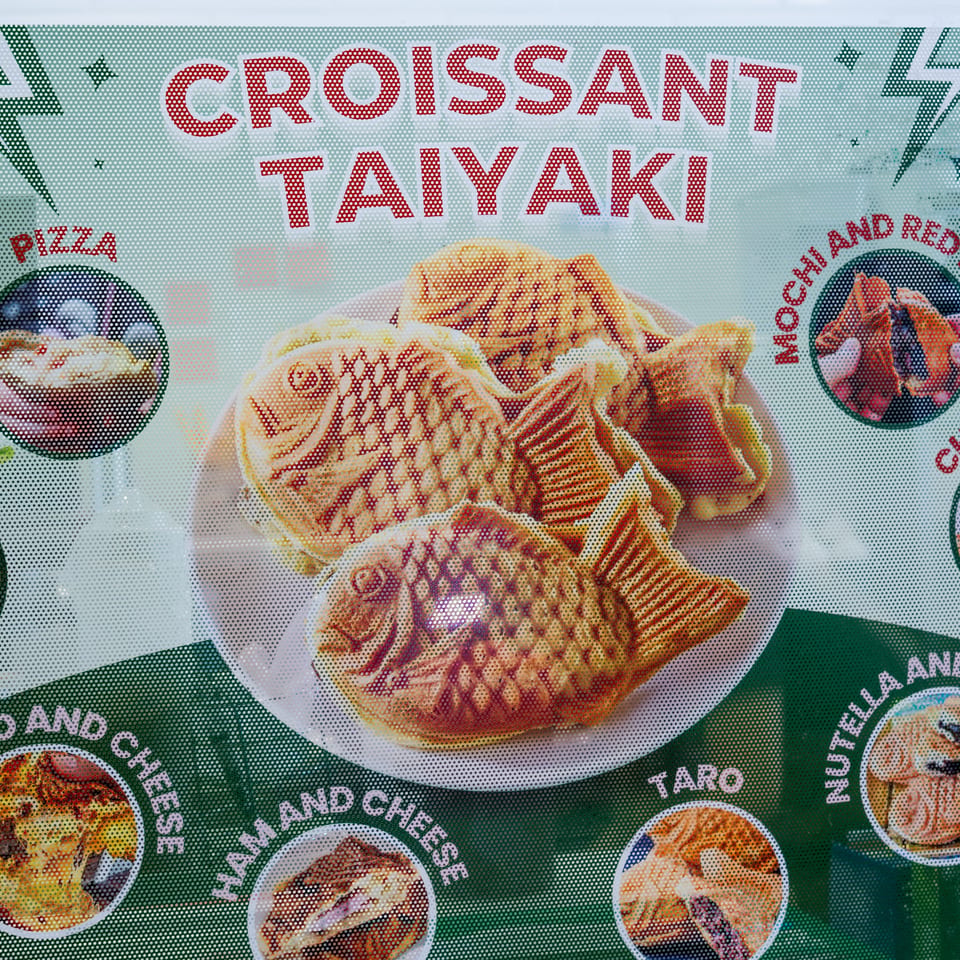 A menu board displays various croissant taiyaki flavors, including pizza, custard, and Nutella banana.